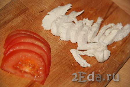 Горячий блин переложить на тарелку. Для приготовления начинки нарезать отварную курицу и помидоры на тонкие ломтики.