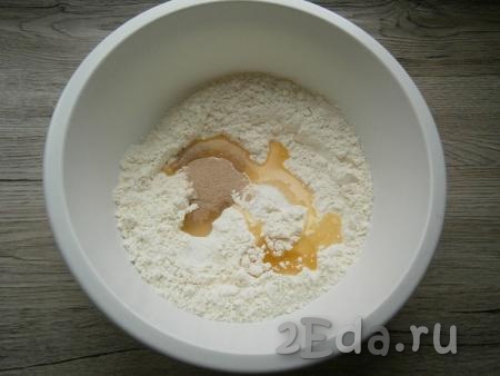 Для приготовления теста в муку всыпать соль и сахар, добавить сухие дрожжи и растительное масло.