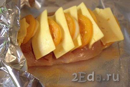 Смазать растительным маслом лист фольги, на него выложить куриное филе с помидорами, сыром и луком.