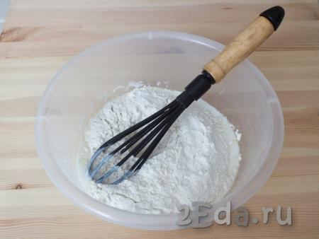 Добавьте муку с разрыхлителем в миску с кефирной массой. Перемешайте венчиком и замесите тесто руками. В какой-то момент может показаться, что тесто жидкое, но следует продолжать замес. Через несколько секунд тесто соберётся в мягкий комок.
