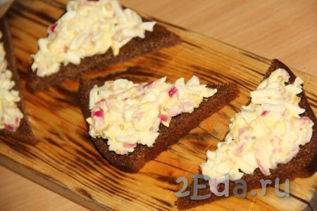 Выложить салат из яиц и маринованного лука на кусочки чёрного хлеба.