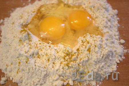 Вначале замесим тесто, для этого на рабочую поверхность нужно высыпать муку, добавить куркуму и щепотку соли. Сделать углубление в муке и вбить яйца.