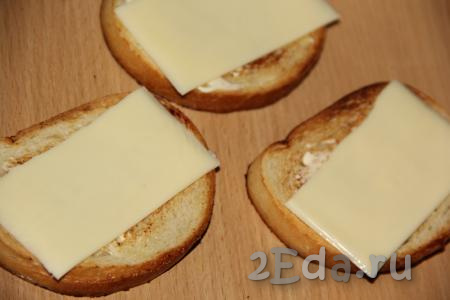 Собрать бутерброды, для этого на каждый обжаренный и остывший кусочек белого хлеба нужно выложить ломтик сыра.