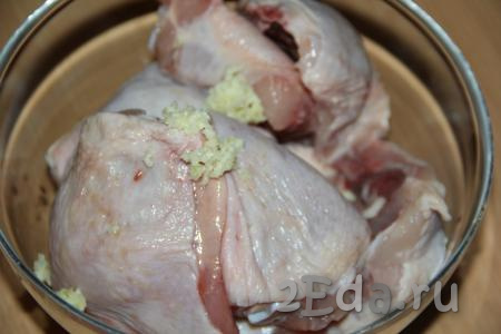 К кусочкам курицы добавить очищенные и пропущенные через пресс зубчики чеснока.