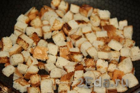 Кусочки белого хлеба нарезать на небольшие кубики и обжарить на сухой сковороде на среднем огне до золотистого цвета со всех сторон. Готовым сухарикам нужно обязательно дать остыть.