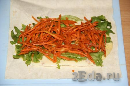 Поверх листьев салата выложить корейскую морковь.