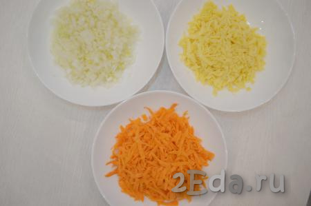 Почистить морковь и лук. Нарезать лук на мелкие кубики. Морковку и твёрдый сыр по отдельности натереть на крупной тёрке, выкладывая их на разные тарелки.