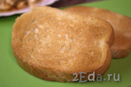 Нарезать на ломтики батон (или белый хлеб), выложить на сухую сковороду и подсушить на среднем огне до золотистого цвета с двух сторон (я подсушила ломтики хлеба в тостере).