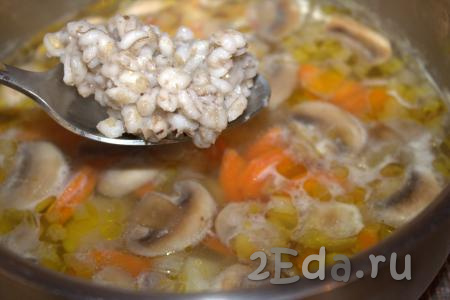 Затем в кастрюлю с супом с шампиньонами, картофелем и обжаренными овощами добавить предварительно отваренную перловку.