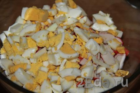 Добавить яйца в миску с салатом из крабовых палочек и корейской моркови.
