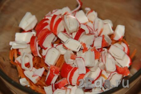 В миску с корейской морковкой выложить крабовые палочки.