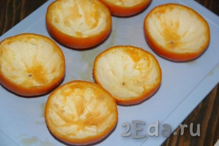Для апельсиновых чашечек лучше использовать мелкие апельсины. Апельсины вымыть, разрезать на две части и с помощью ложки удалить мякоть. Выложить апельсиновые чашки в силиконовые формочки для кексов.