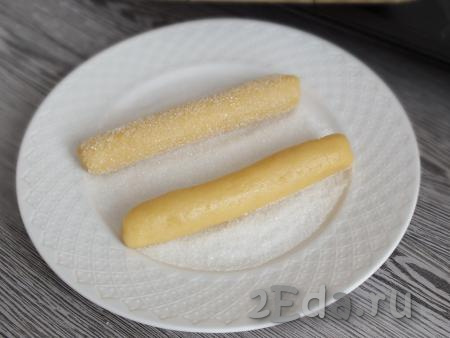 В тарелку насыпьте 2 столовые ложки сахара (лучше будет, если это сахар мелкого помола). Обваляйте в сахаре будущее печенье со всех сторон.