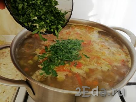 Через пару минут после горошка добавить в суп чеснок и зелень. Довести суп до кипения, выключить огонь. Оставить блюдо настаиваться под крышкой на 10-20 минут.