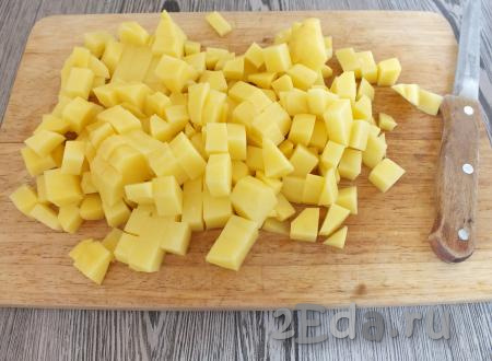 Очищенный картофель нарежьте средним кубиком и опустите в бульон. Варите на среднем огне.