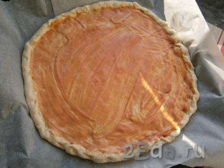 Далее тесто раскатать в большую лепёшку толщиной около 0,5 см (можно разделить тесто на 2 пиццы). Выложить лепёшку на противень, застеленный бумагой. Сделать небольшой бортик по краю теста. Смазать лепёшку кетчупом, смешанным с майонезом.