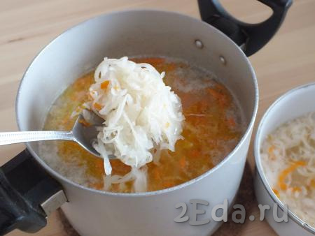 Как только картофель сварится, в суп с перловкой добавьте обжаренные лук и морковь, отваренную квашеную капусту, если нужно, посолите и варите рассольник 15 минут.