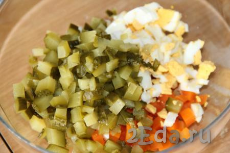 Солёные огурчики нарезать на средние кубики и выложить в салат из варёных яиц и моркови.