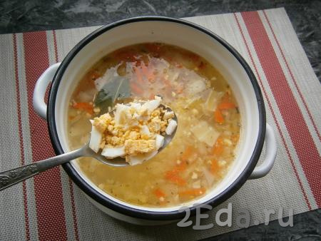 Когда суп с капустой проварится 10 минут, выложить в него обжаренные лук с морковью, перемешать, добавить лавровый лист и рубленные варёные яйца.