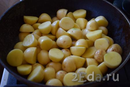 В разогретое масло выкладываем молодой картофель в кожуре и равномерно распределяем его по всей поверхности сковороды.