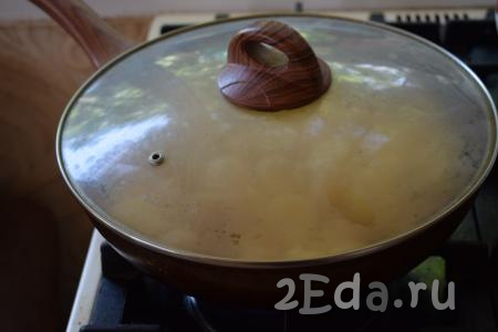 Далее накрываем сковороду крышкой и жарим молодую картошку на огне чуть выше среднего, примерно, 7-8 минут.