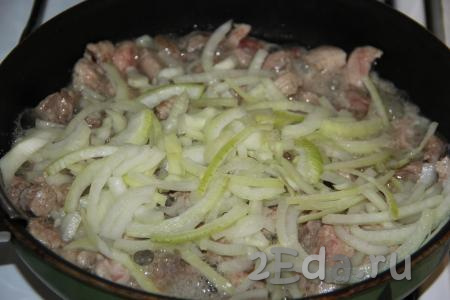 Обжарить кусочки свинины на среднем огне, иногда перемешивая, в течение 5 минут. Почистить и нарезать полукольцами луковицу, а затем выложить в сковороду со свининой.