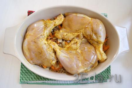 Перемешать гречку с овощами и разровнять. Сверху выложить куриные окорочка.