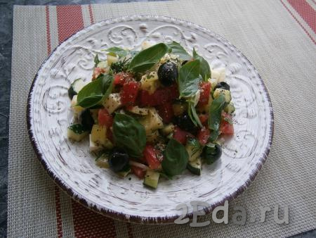 Салат с огурцами, помидорами и моцареллой выложить в салатник (или на плоскую тарелку), посыпать свежемолотым чёрным перцем, орегано и разложить сверху листики зелёного базилика.