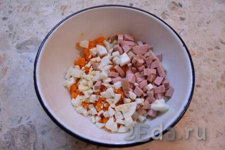В салат к картофелю и моркови добавить рубленные вареные яйца и нарезанную небольшими кубиками колбасу.