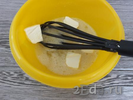 К смеси сахара и яиц добавьте кусочки сливочного масла комнатной температуры, перемешайте венчиком яично-масляную смесь.