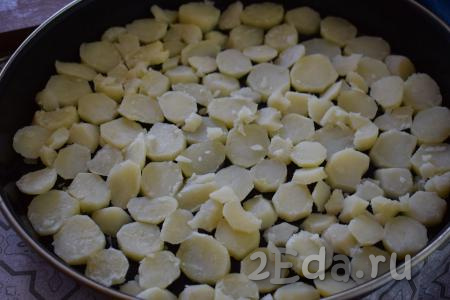 В форму для запекания (или на противень) кладём кусочки сливочного масла, сверху выкладываем кружочки картофеля.