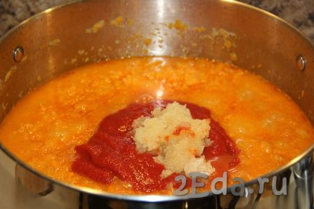 По прошествии 1,5 часов в кастрюлю с кабачковой икрой добавить чеснок и томатную пасту.