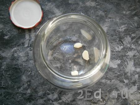 На дно предварительно простерилизованной банки ёмкостью 1,5 литра выложить очищенные зубчики чеснока.