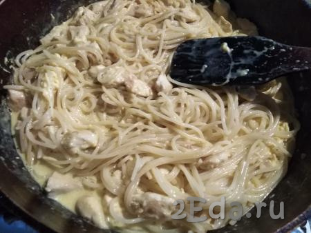 К спагетти с курицей вливаем соус и хорошо перемешиваем, чтобы соус полностью покрыл мясо с макаронами и немного прогрелся. 