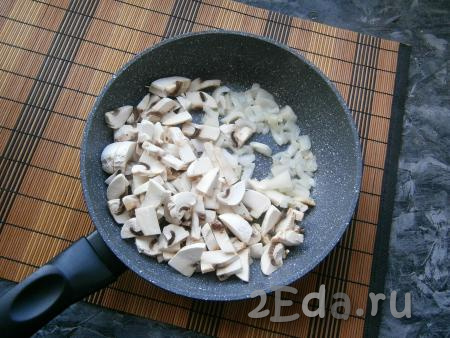 Морковь и лук очистить. Сковороду с маслом и грибами разогреть, добавить в неё луковицу, нарезанную небольшими кусочками, обжарить на среднем огне минуты 2-3, не забывая иногда перемешивать.