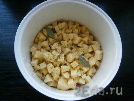 В чашу выложить нарезанный кубиками очищенный картофель, добавить соль, специи, лавровые листья.