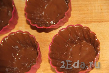 Нанести шоколад с помощью силиконовой кисточки в два слоя на стенки каждой силиконовой формочки и поставить в морозилку минут на 15-20 (до полного застывания шоколада). Часть растопленного шоколада оставить для нанесения в дальнейшем поверх творожной массы.