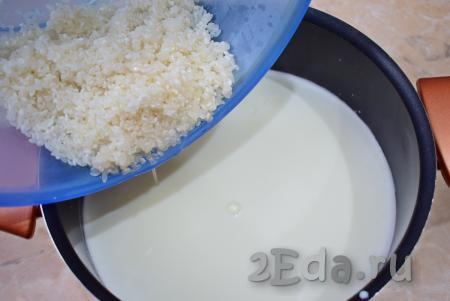 Затем добавьте в молоко промытый рис и перемешайте. Доведите до кипения и накройте кастрюлю крышкой. Сделайте минимальный огонь и оставьте кашу вариться минут на 15, периодически помешивайте.