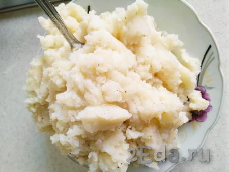 Готовность картофеля проверяем вилкой или ножом (если картофель мягкий, легко прокалывается, значит он готов). Сливаем всю воду из кастрюли в ёмкость, чтобы в дальнейшем, при необходимости, добавлять эту жидкость в наше пюре. Разминаем картофель толкушкой, добавляем немного воды, в которой варилась картошка (которую мы ранее слили), сливочное масло, чёрный молотый перец по вкусу. При необходимости, подсаливаем пюре по вкусу. Перемешиваем. Готовое пюре не должно быть жидким.