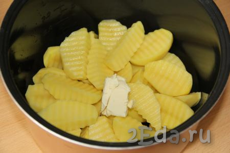 В чашу мультиварки выложить картофель, добавить кусочек сливочного масла.