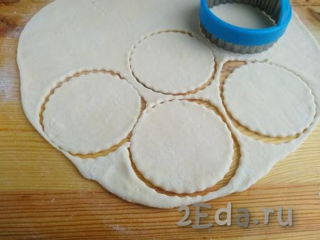 На столе, присыпанном мукой, раскатать тесто в пласт толщиной 2 мм. Выемкой (или стаканом) диаметром около 9-10 см вырезать кружки.
