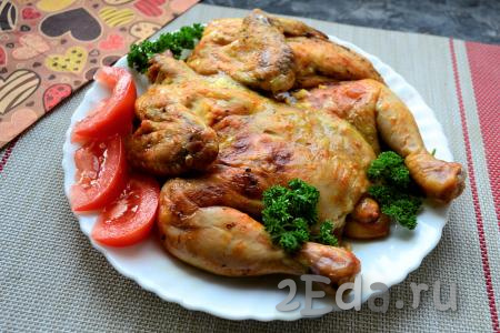 Разместить цыпленка на тарелке, украсить овощами и зеленью.