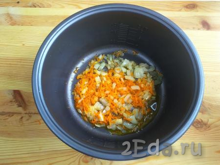 В чашу мультиварки налить растительное масло. Установить режим "Выпечка" на 20 минут. Выложить лук с морковью, жарить с открытой крышкой 10 минут, иногда помешивая.