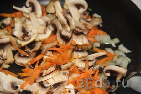 Добавить грибы в сковороду с морковкой и луком, обжаривать шампиньоны с овощами в течение 10 минут, иногда перемешивая.