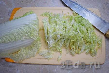 Пока курочка жарится, займитесь подготовкой овощей. С пекинской капусты снимите пару верхних листиков (они нам не понадобятся). Затем разрежьте кочан по всей длине и нашинкуйте.