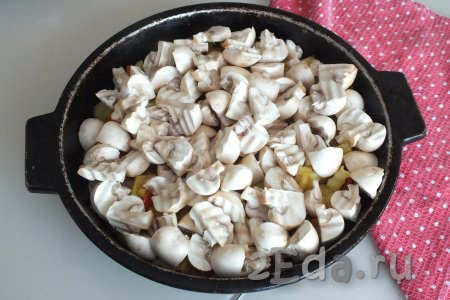 Добавьте к овощам нарезанные шампиньоны, перемешайте, прикройте крышкой и тушите овощное рагу с грибами на огне чуть ниже среднего 5-7 минут.