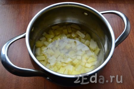 Картофель очистить и нарезать небольшими кубиками в кастрюлю, залить водой.