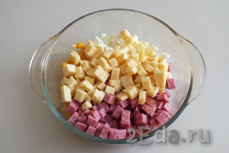 В салатник с яйцами и кукурузой добавьте нарезанные колбасу и сыр.