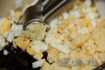 В салатнике соединить нарезанные свеклу, яйца и сыр, добавить соль, сюда же выдавить через пресс очищенный зубчик чеснока, перемешать.