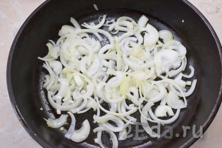 Налейте в сковороду немного растительного масла, разогрейте, выложите лук, нарезанный полукольцами, и обжарьте его до прозрачности (на это потребуется 3-5 минут). Периодически перемешивайте, чтобы он не начал подгорать.